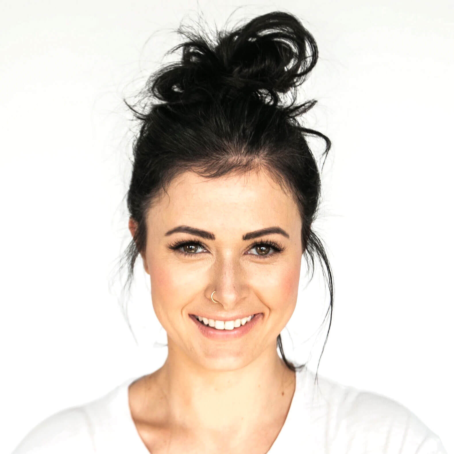A woman with a messy bun is smiling for the camera.